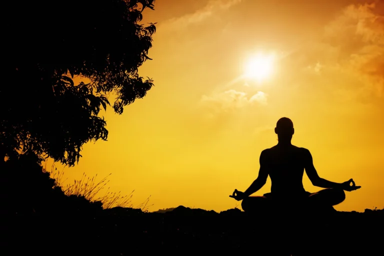 Silhouette of a person meditating at sunrise