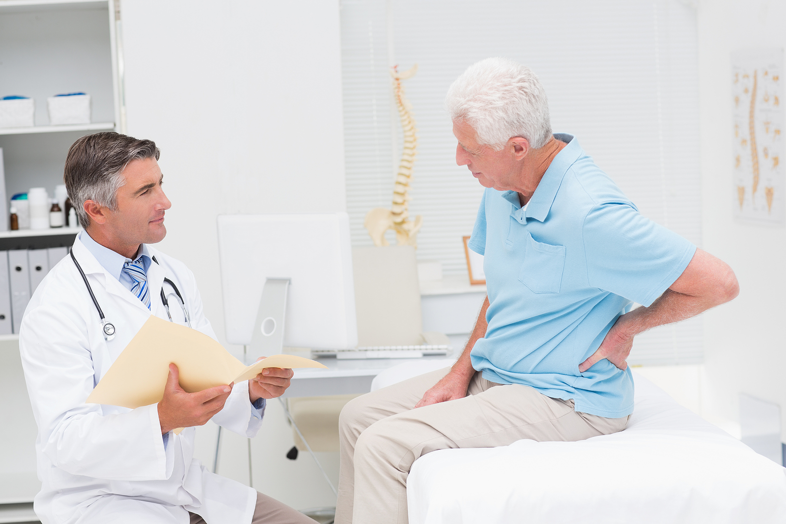 Practitioner reviewing patient history with a man experiencing lower back pain