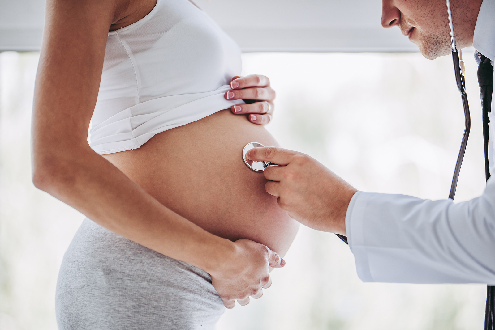 Pregnant woman having her belly checked with a stethoscope