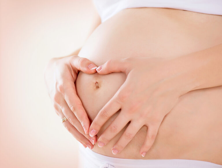 Pregnant woman making a heart shape with her hands on her bump