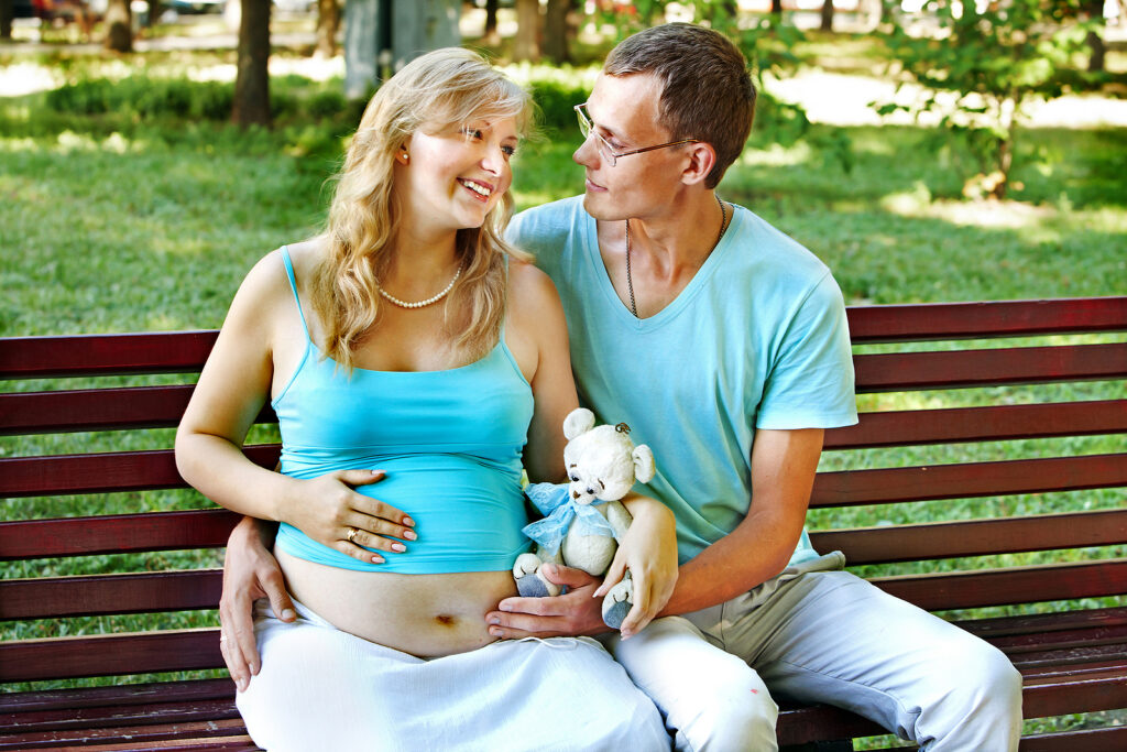 Expecting couple relaxing together on a park bench