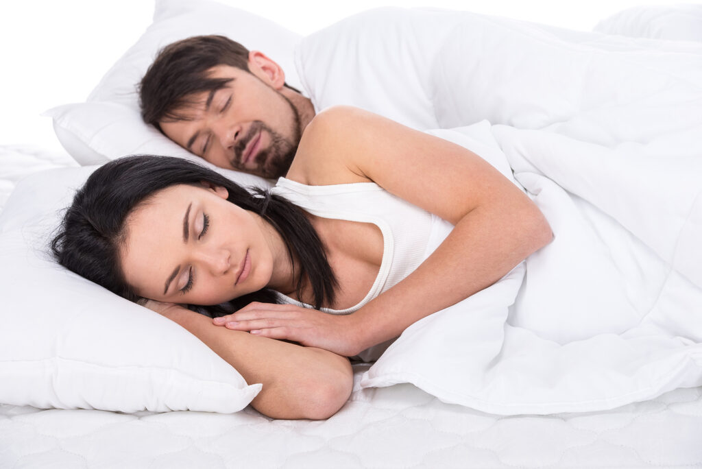 Couple sleeping undisturbed in a cool, dark, quiet bedroom environment
