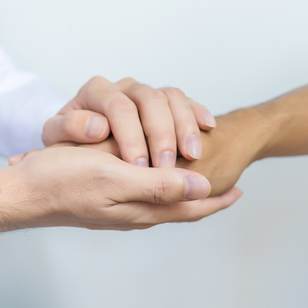 Practitioner's hands offering reassurance to a patient