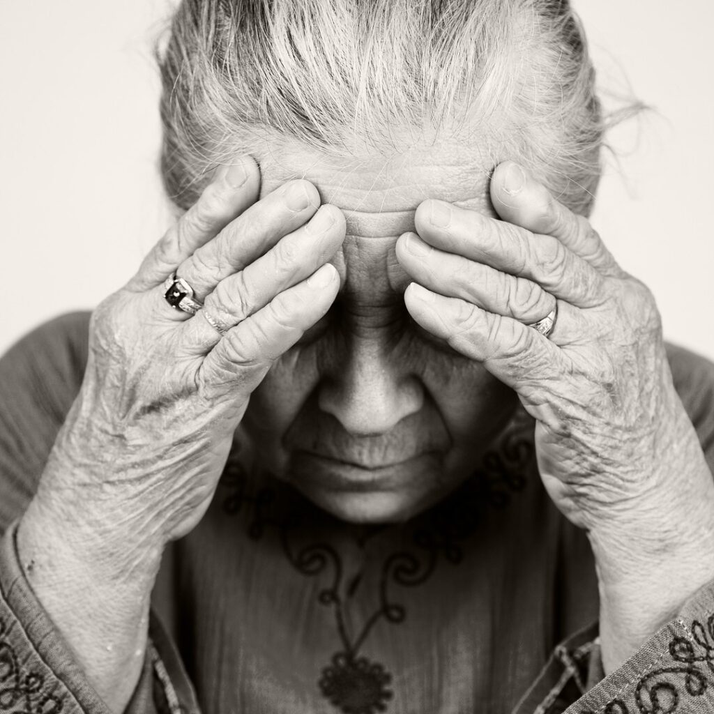 Headaches Migraines Auckland 2 Older woman holding both hands to her forehead with a headache