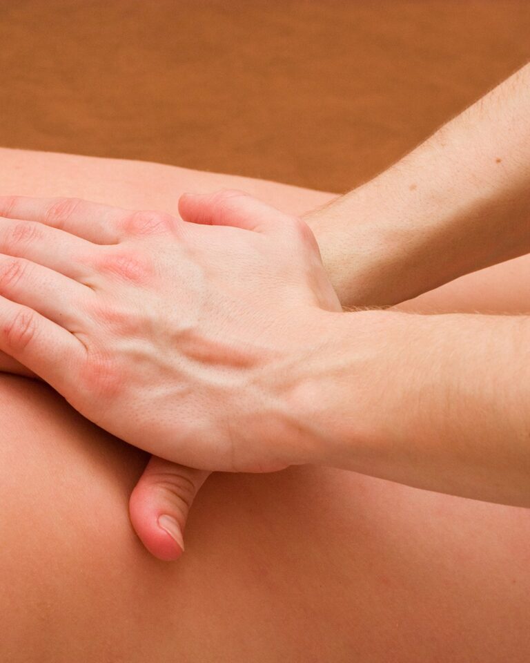 Massage therapist working both palms firmly along a client&rsquo;s back