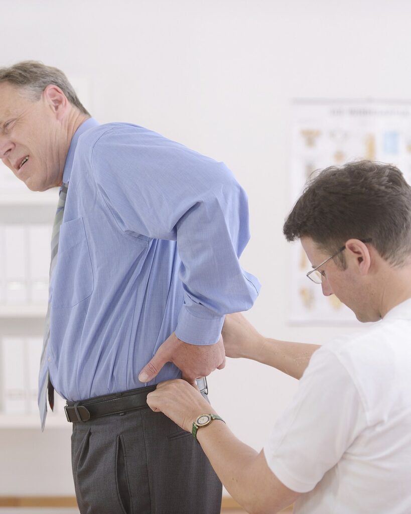 Osteopath examining an older patient&rsquo;s back