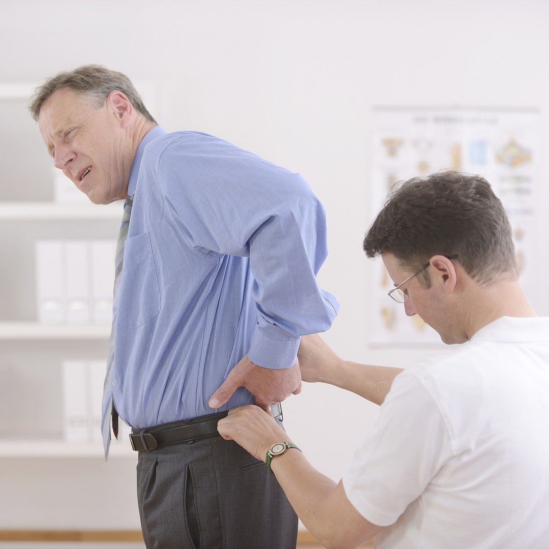 Osteopath examining an older patient's back